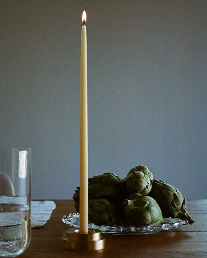 GLŌAM thin taper golden brass holder, a sculptural minimalist brass base made for Thin refined beeswax tapers. solid polished brass.