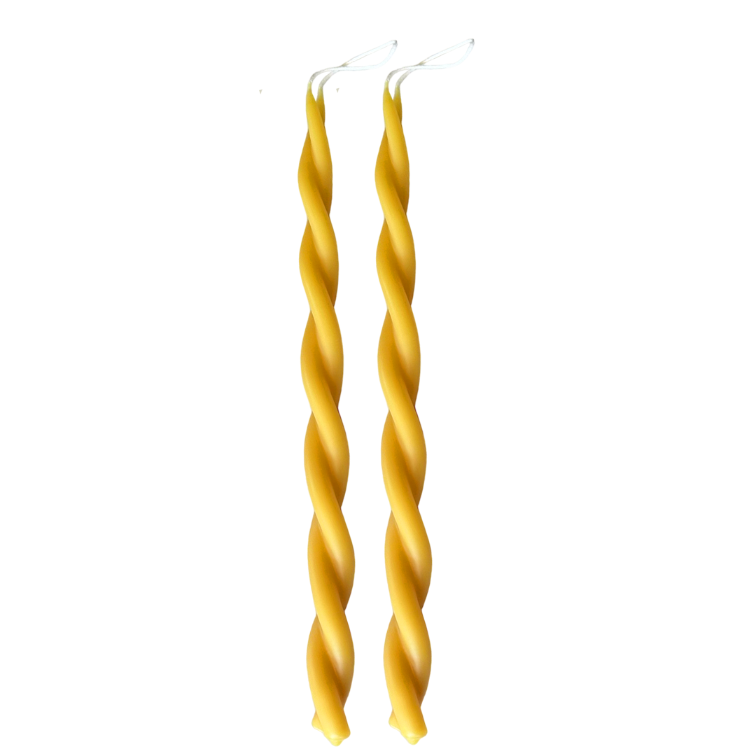 A pair of GLŌAM hand-twisted beeswax candles in natural, a yellow hue, crafted with plant-based pigments.