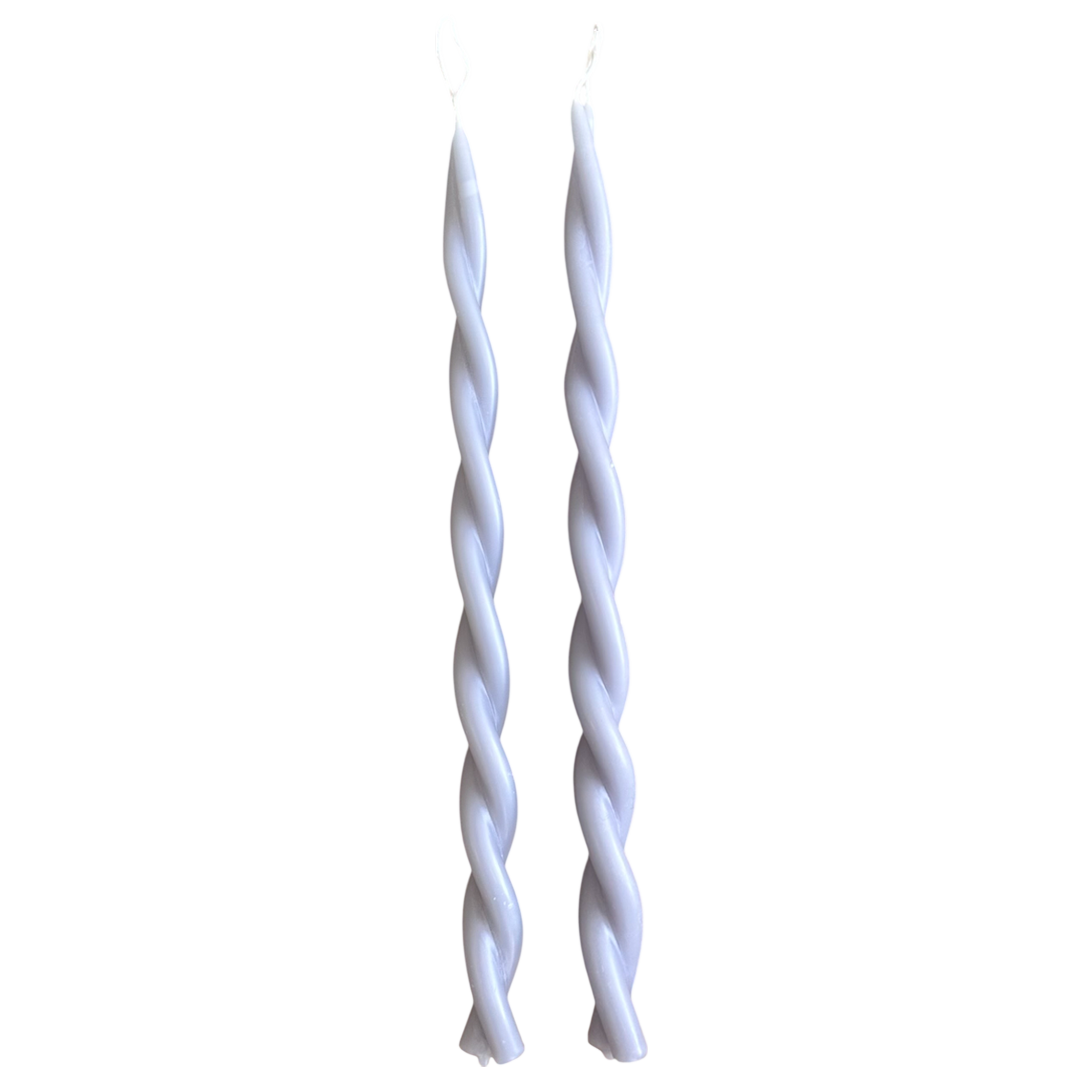 A pair of GLŌAM hand-twisted beeswax candles in lavender, a light purple hue, crafted with plant-based pigments.