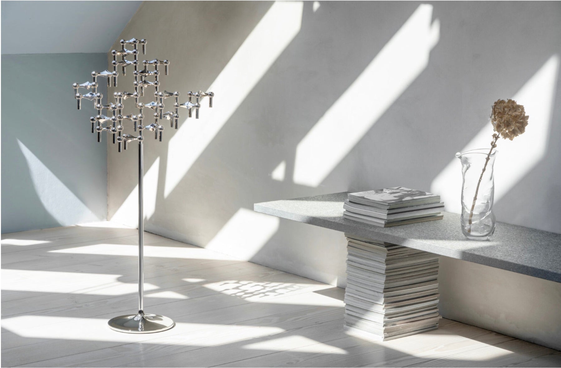 STOFF Nagel Floor Stand, a tall multi-arm silver metal floor lamp stands in a minimalist room with dramatic diagonal sunlight and shadows. 