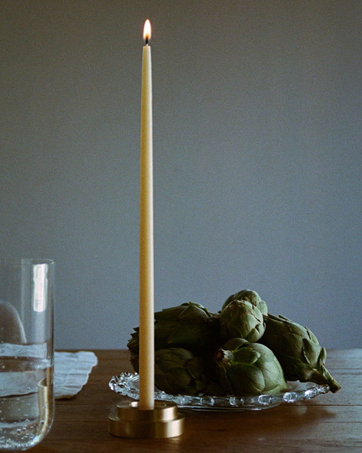 GLŌAM thin taper golden brass holder, a sculptural minimalist brass base made for Thin refined beeswax tapers. solid polished brass.