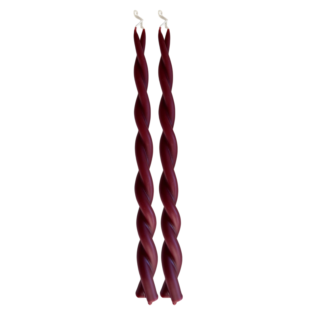 A pair of GLŌAM hand-twisted beeswax candles in Vin Chaud, a dark-red hue, crafted with plant-based pigments.
