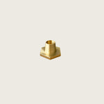 GLŌAM hexagon candlestick, a golden brass taper candle holder for Classic and Twisted beeswax tapers, solid polished brass on a dining table