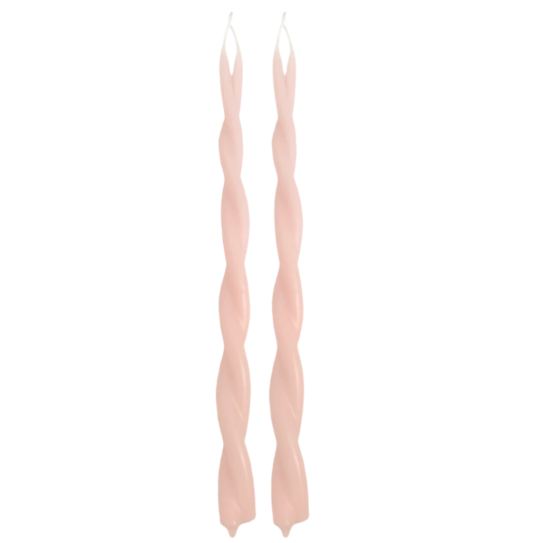 A pair of GLŌAM hand-twisted beeswax candles in scallop, a light-pink hue, crafted with plant-based pigments.