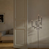 STOFF Nagel chrome floor stand with lit taper candles standing in a doorway of a modern living room