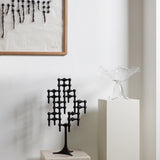 STOFF Nagel black stand built into a candle composition on a plinth in a modern interior