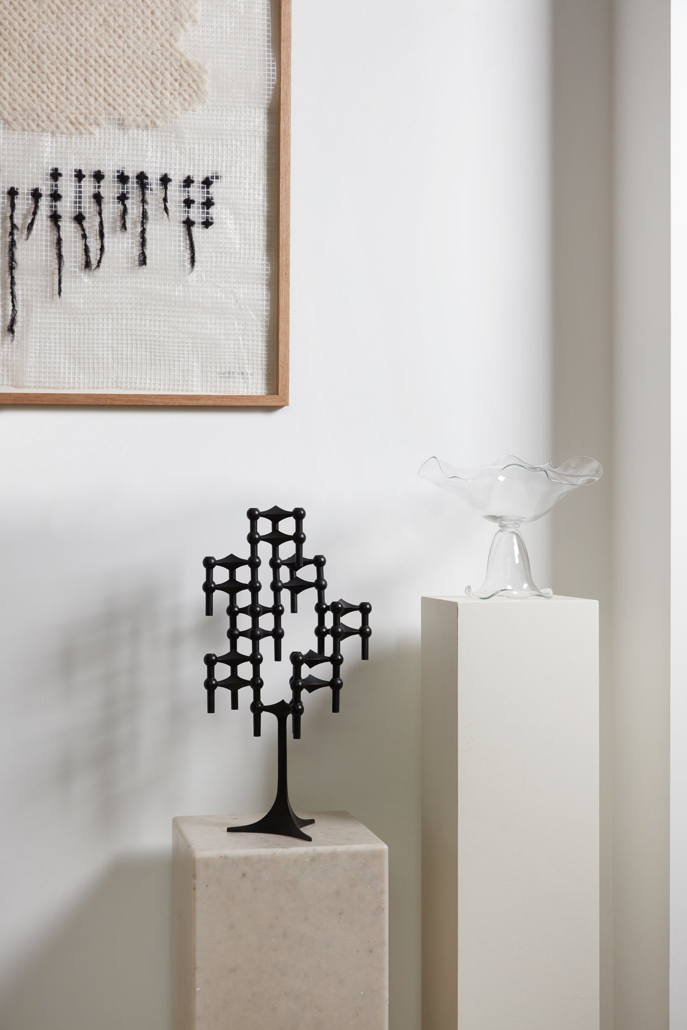 STOFF Nagel black stand built into a candle composition on a plinth in a modern interior