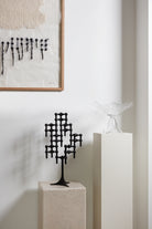 STOFF Nagel black stand built into a candle composition on a plinth in a modern interior