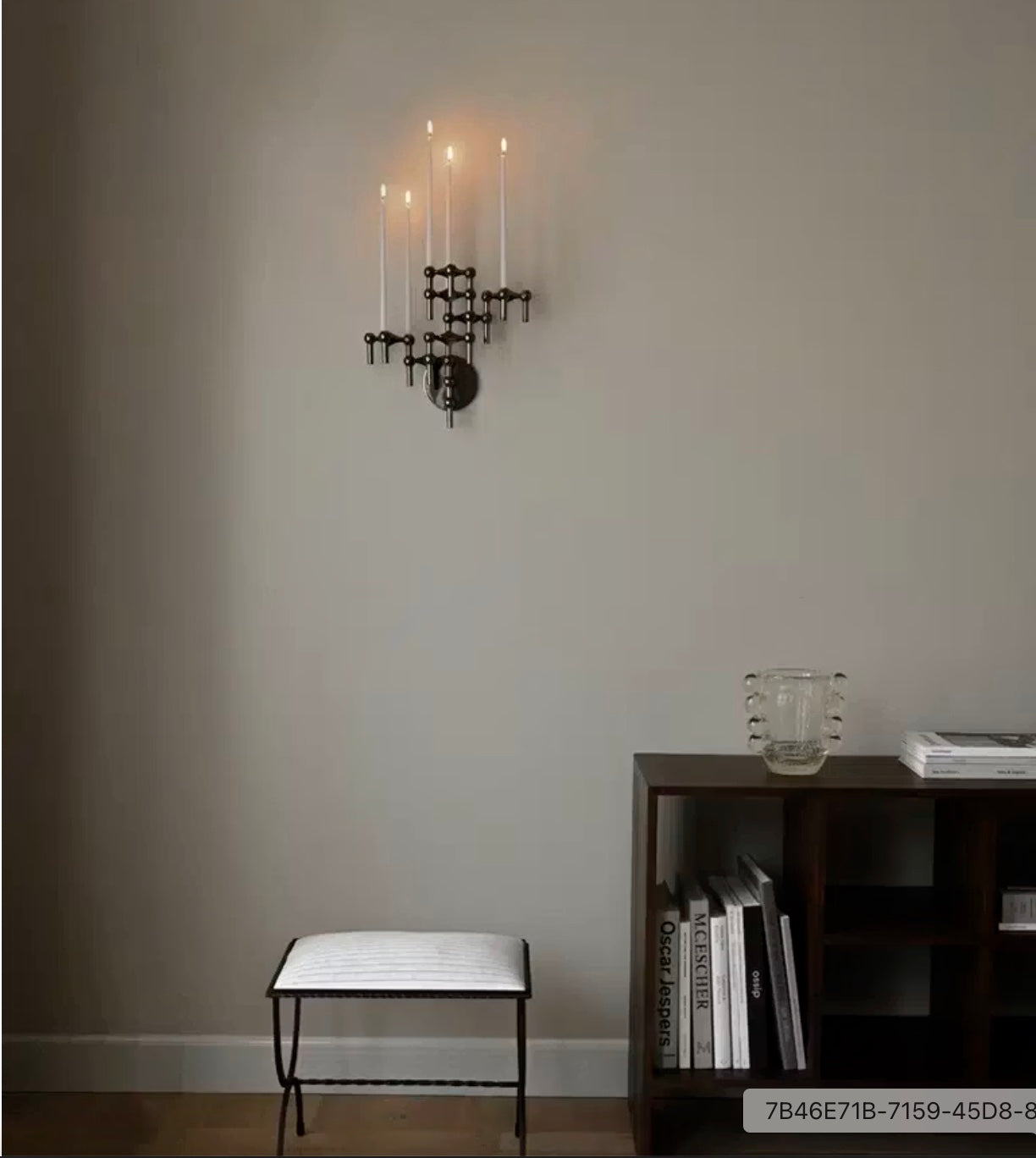 STOFF Nagel black wall hanger mounted in a living room, holding lit taper candles above a bench and shelves