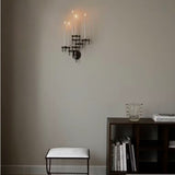 STOFF Nagel black wall hanger mounted in a living room, holding lit taper candles above a bench and shelves