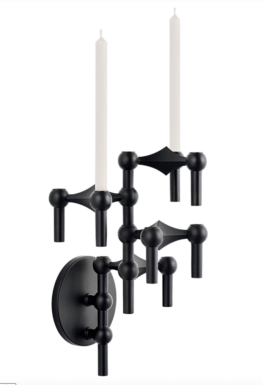 STOFF Nagel wall hanger in matte black holding a vertical arrangement of modular candle holders with lit taper candles