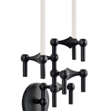 STOFF Nagel wall hanger in matte black holding a vertical arrangement of modular candle holders with lit taper candles