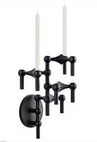 STOFF Nagel wall hanger in matte black holding a vertical arrangement of modular candle holders with lit taper candles