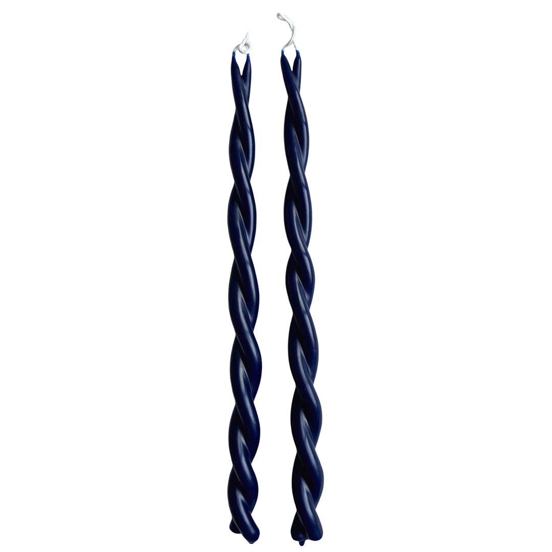 A pair of twisted pure beeswax taper candles in oxford blue infused with plant-based pigments  